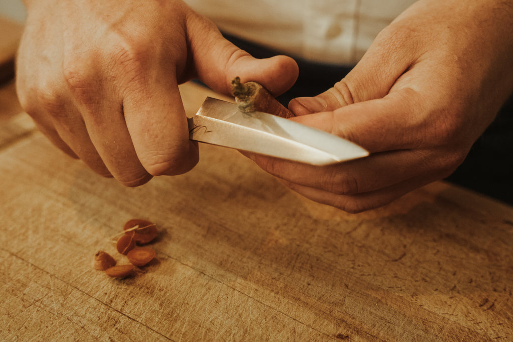 mains tenant un couteau d'office découpant des carottes