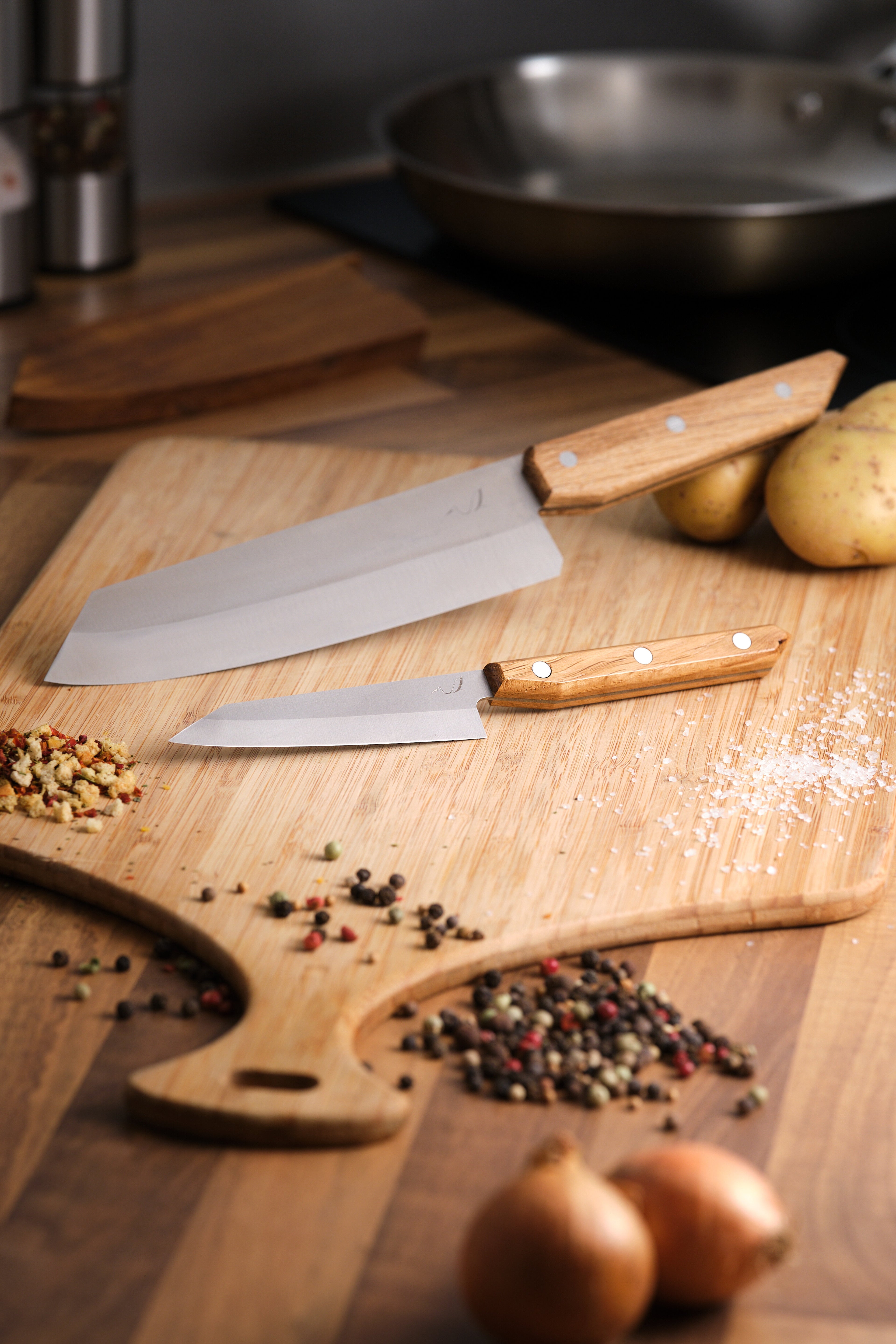 Couteau de cuisine et couteau d'office sur une planche en bois avec des grains de poivre