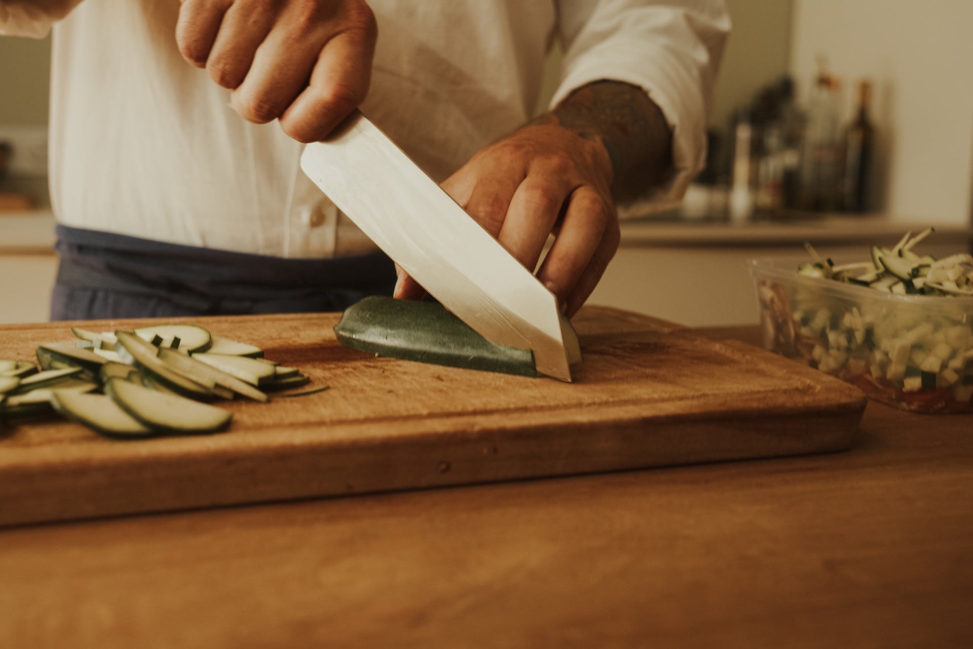 chef tenant un couteau de cuisine coupant des lamelles de courgettes