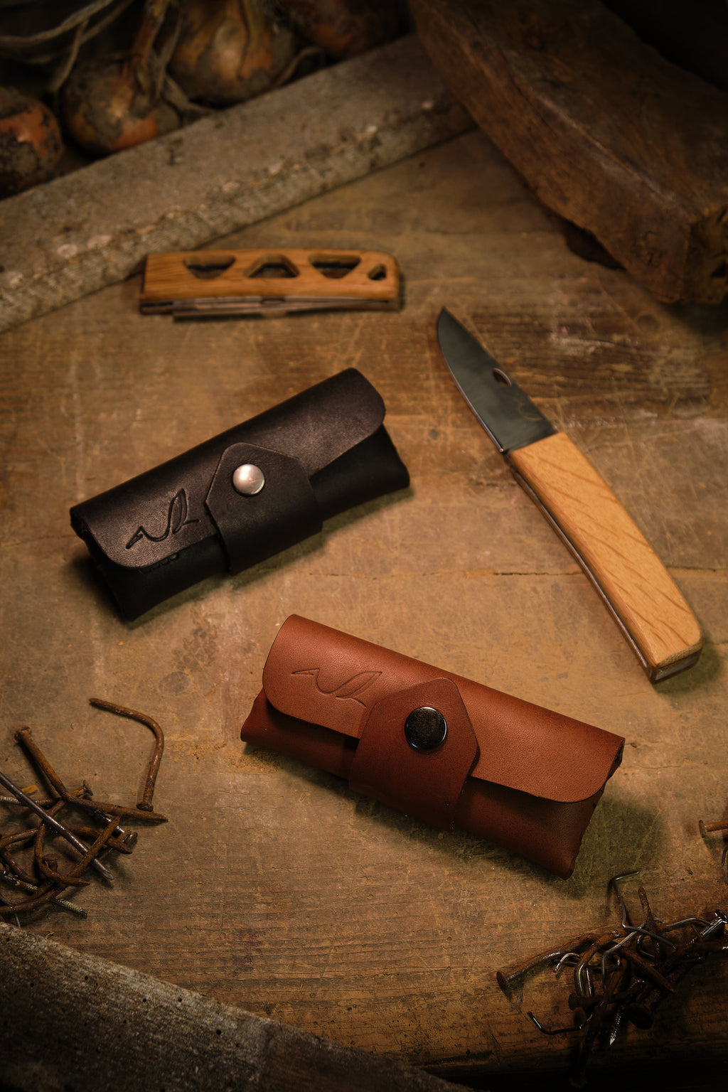 couteau pliant à coté d'étui à couteau en cuir noir et brun