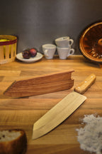 Couteau de cuisine et son étui en bois sur une planche à découper avec des ingrédients 