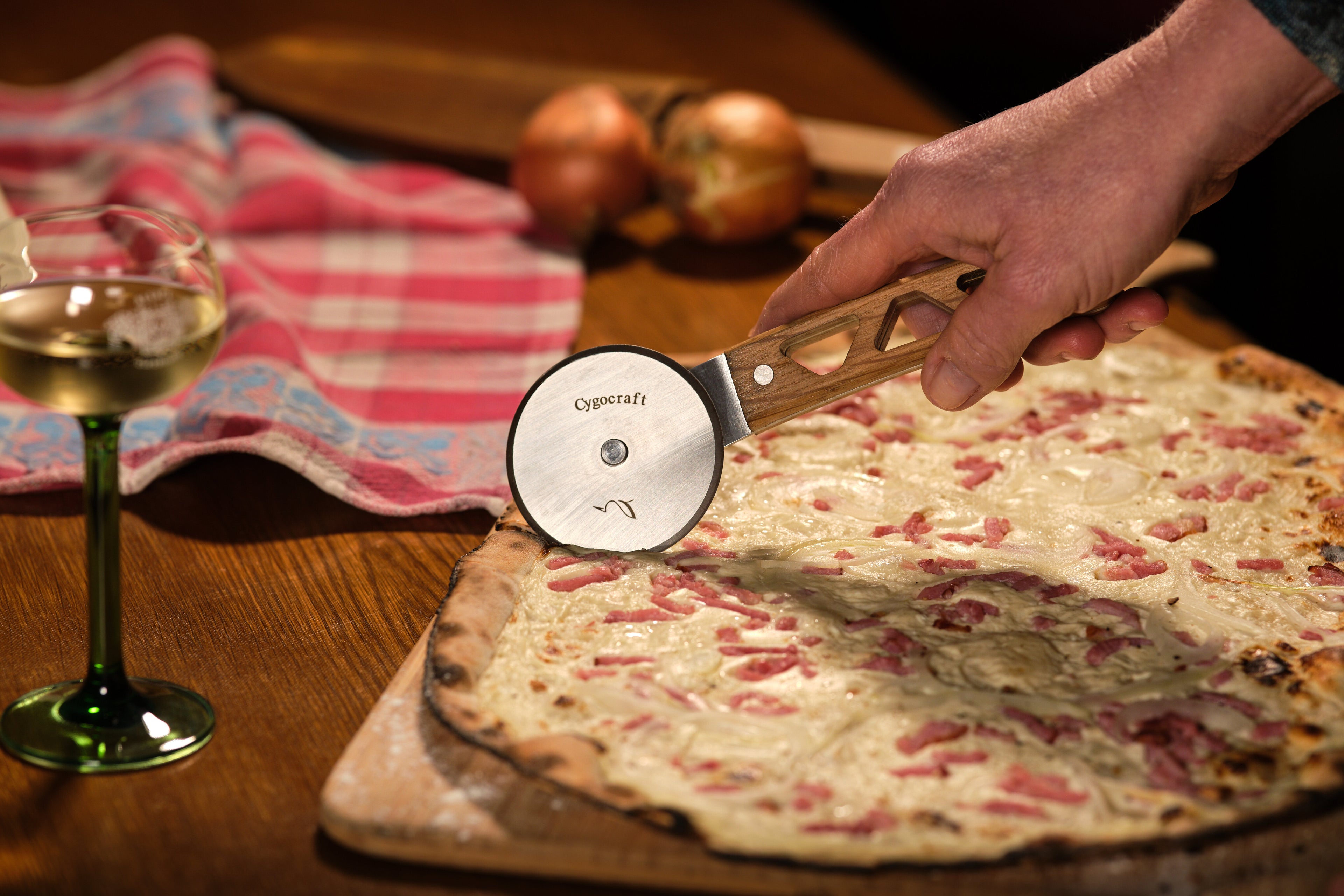 personne tenant une roulette à tarte coupant une tarte